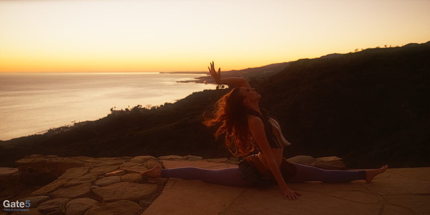 A woman strikes a beautiful yoga pose at sunset in Malibu California