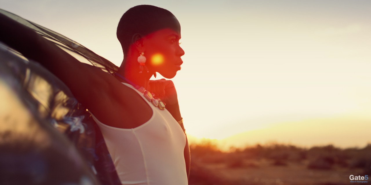 a sun flare covers the profile of a woman in the desert in a fashion film