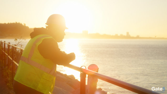 a construction worker looking out at the ocean in the morning sunrise